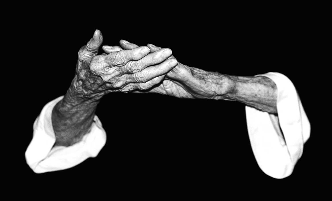Older person, hands gently touching, black and white