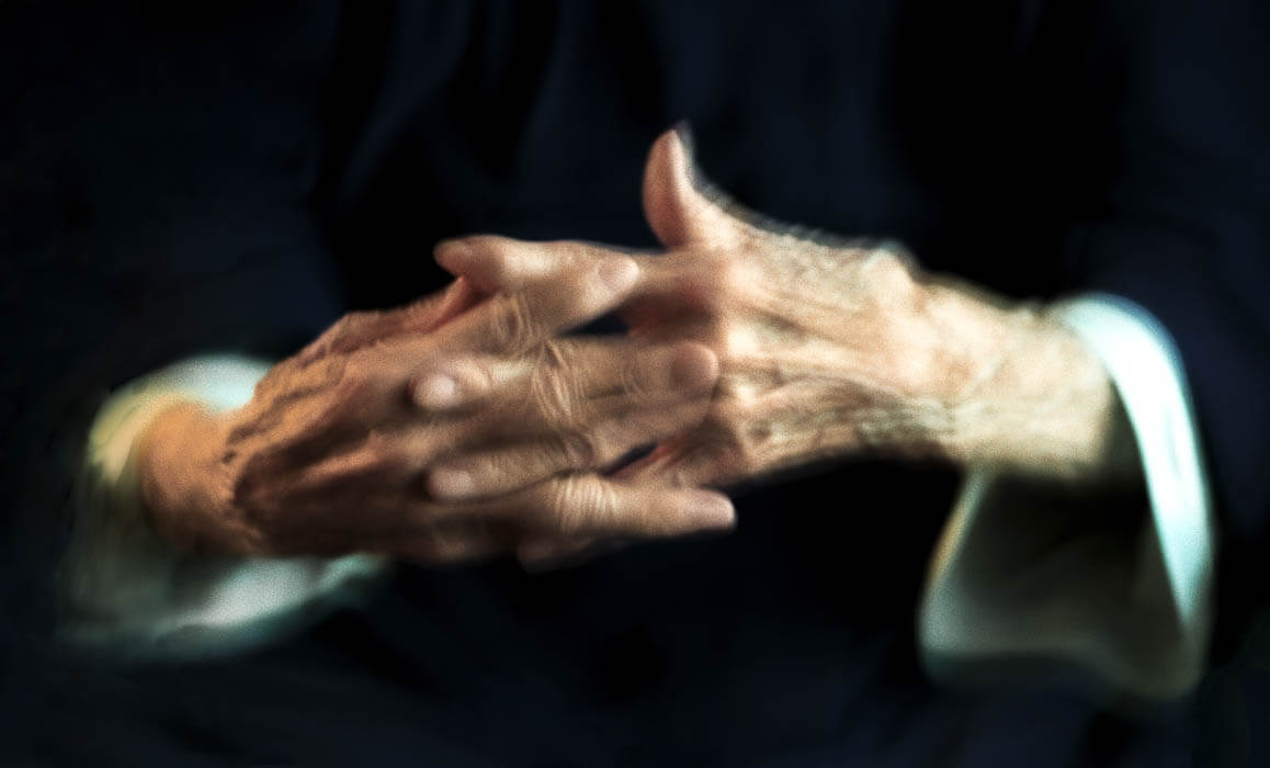 old hands with fingers bound together in a blur