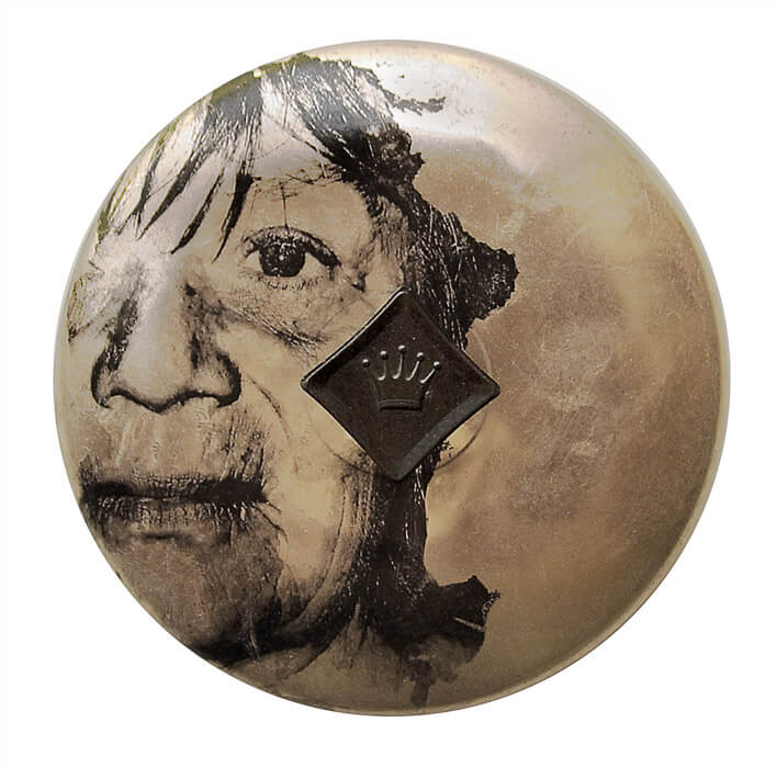 image transfer of the tired face of a woman on a metal pot lid with a crown handle
