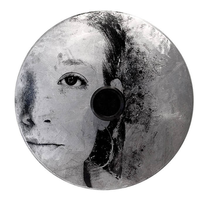 image transfer, face of a woman, big earrings, carbon, on a textured metal surface (pot lid with handle))