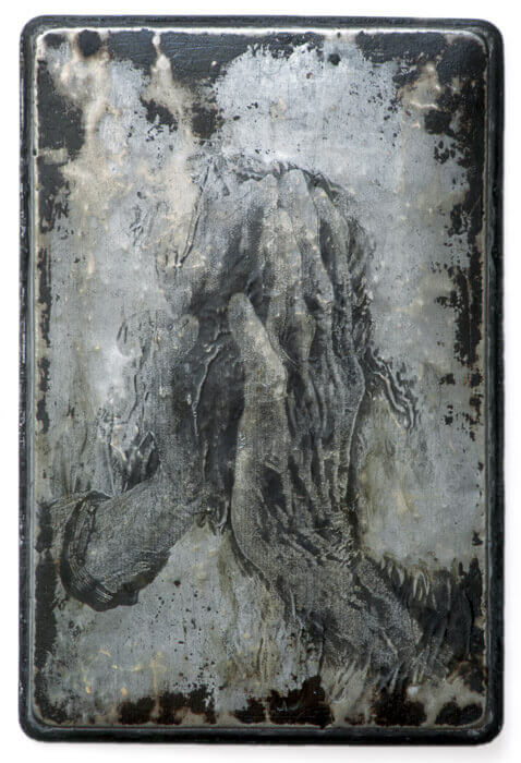 image transfer of hands touching on to a banged up, burnt found object (a metal pan)