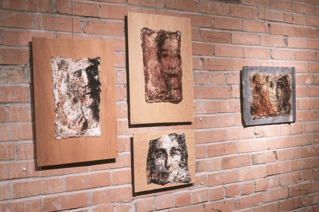 4 skins of acylic with embedded rust and carbon with faces showing through, mounted on wood and metal