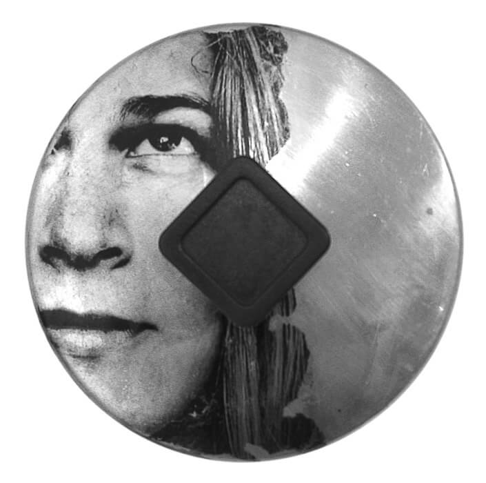 photo transfer of the face of a young woman looking up with eyes wide open on a round found object (pot lid), square handle