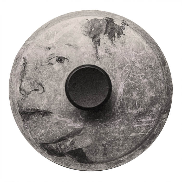 The translucent face of a women on a round pot lid with a lacy patina