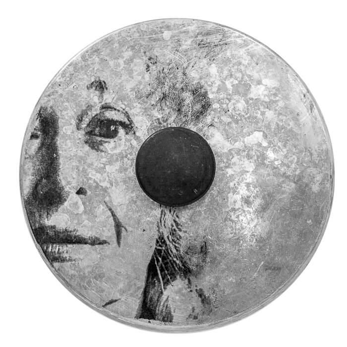 hazy patina on a metal pot lid, woman's face appears to be looking out and through the patina